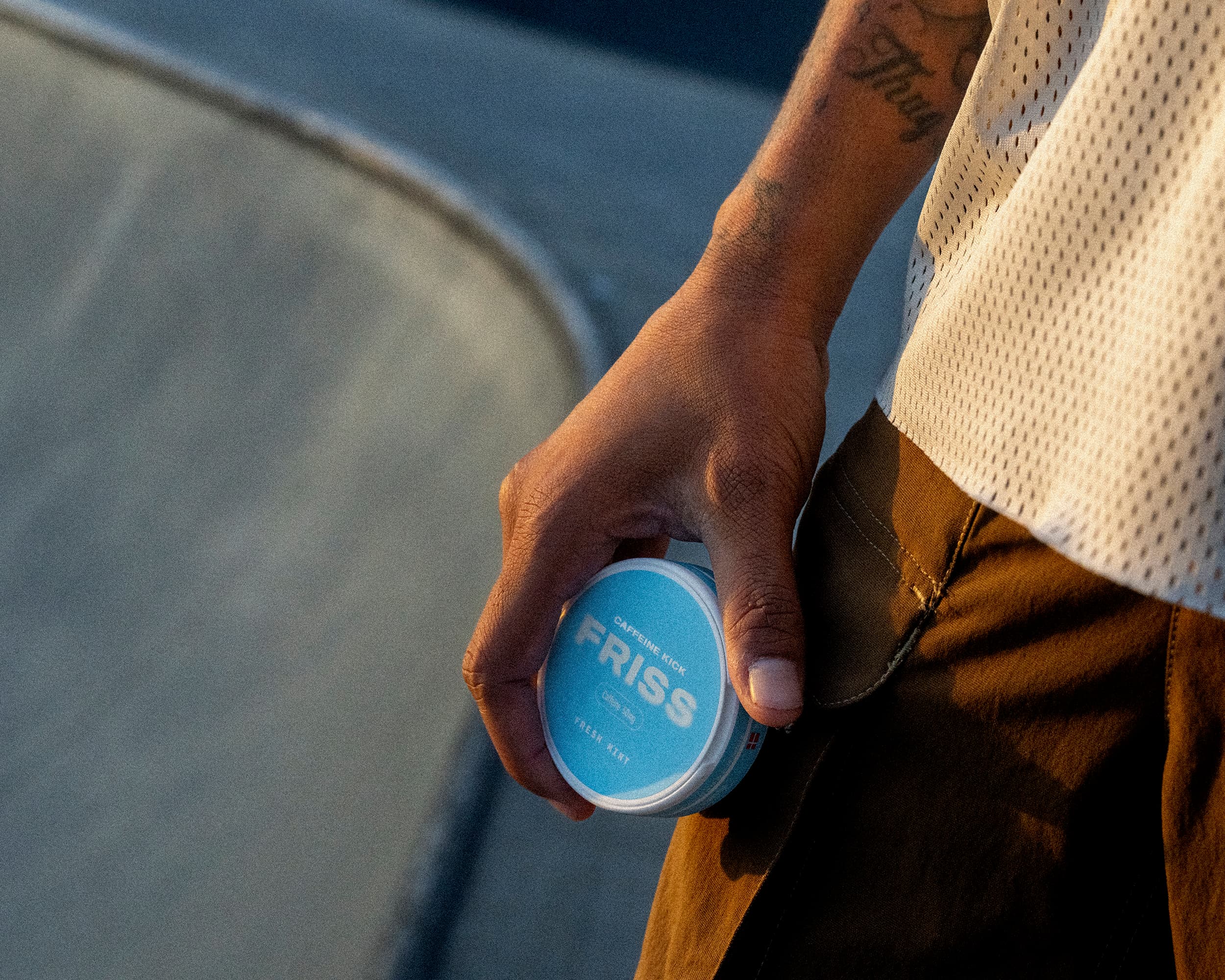 FRISS brand campaign photograph, product in hand at a skate park at golden hour
